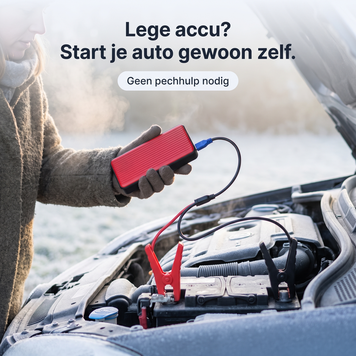 Draagbare auto starthulp in de hand, met kabel aangesloten op de accu